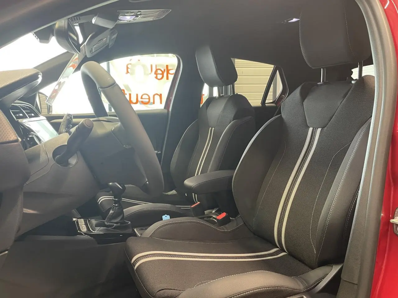Intérieur avant de l’Opel Corsa rouge 2026, vue côté conducteur montrant sièges sport noirs avec bandes blanches.