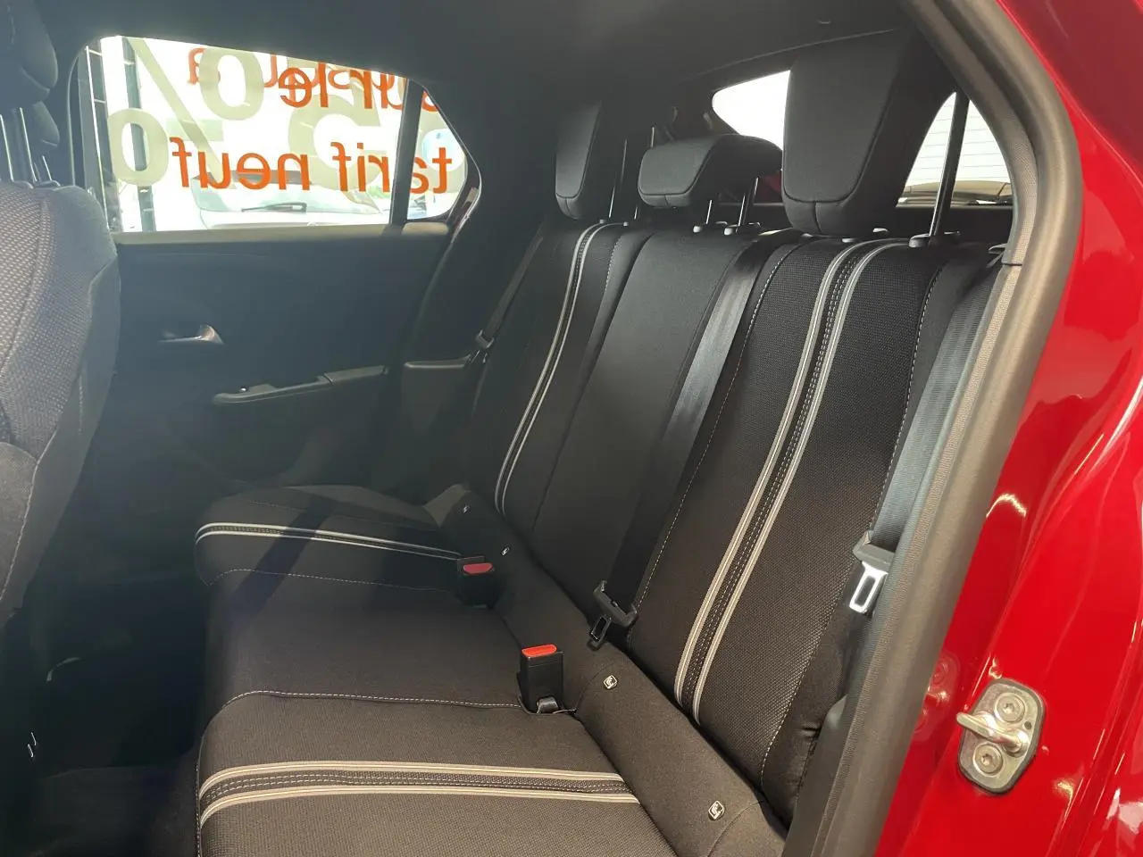 Vue intérieure côté droit sur la banquette arrière noire avec surpiqûres blanches d’une Opel Corsa rouge.