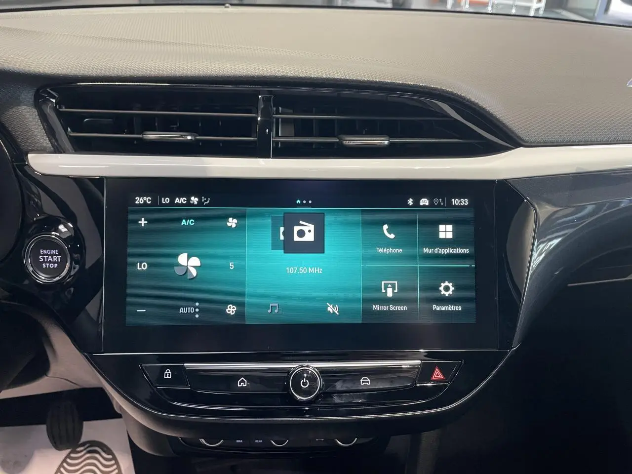 Écran tactile 10 pouces central de la console d’une Opel Corsa rouge, affichant la climatisation et les options multimédia.
