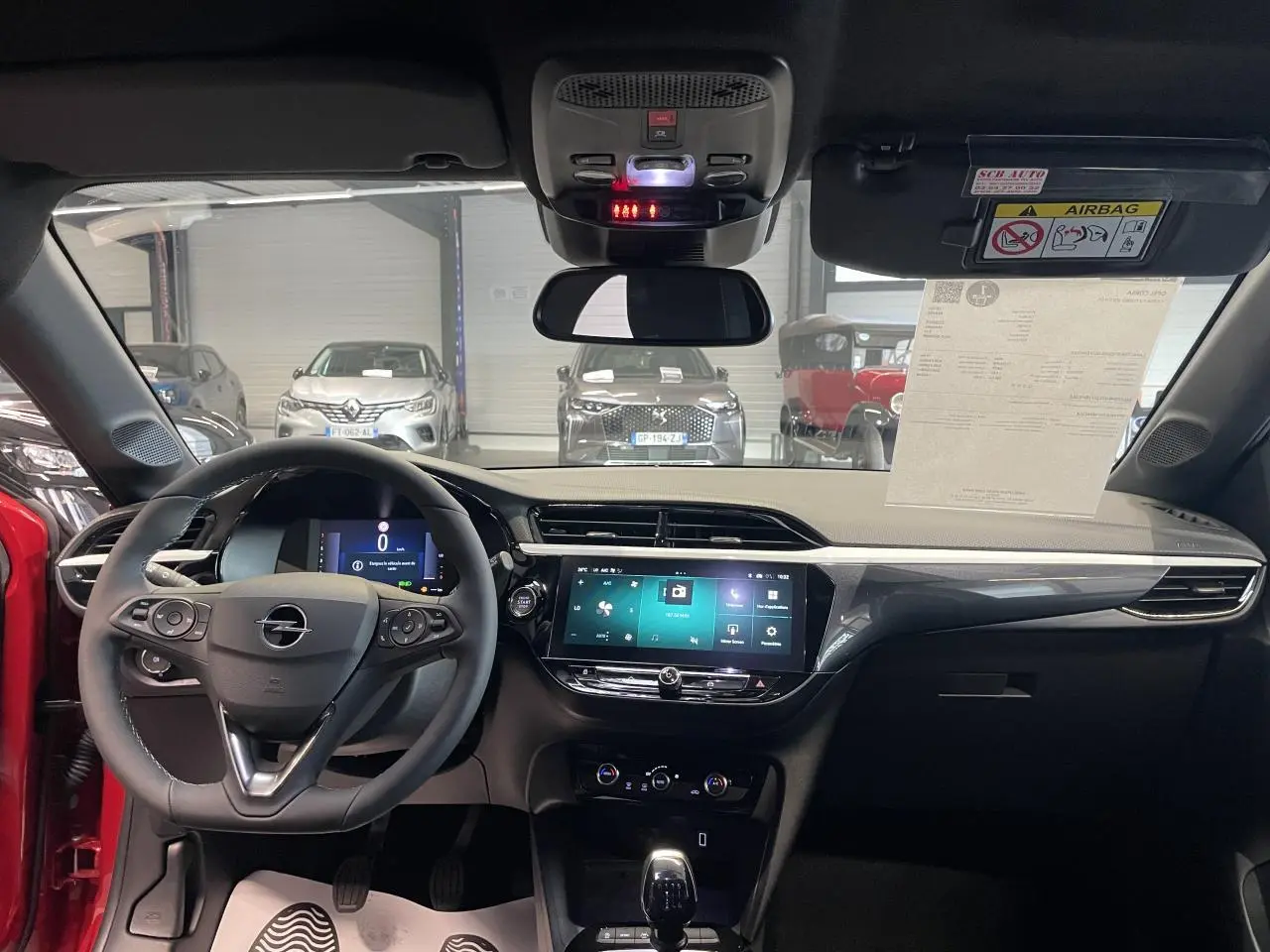 Vue intérieure avant de l’Opel Corsa rouge 2026, tableau de bord moderne avec écran tactile 10 pouces et volant multifonction.