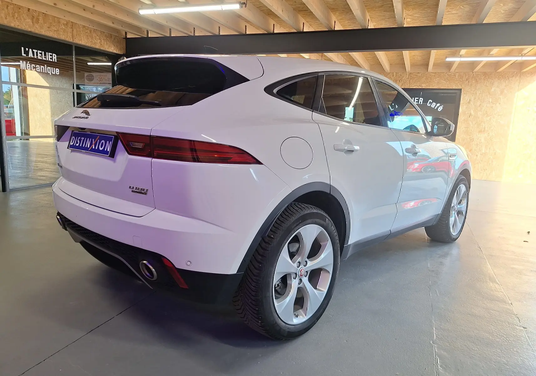 Vue 3/4 arrière droite d'un Jaguar E-PACE blanc 2019 avec feux arrière LED et double sortie d'échappement.