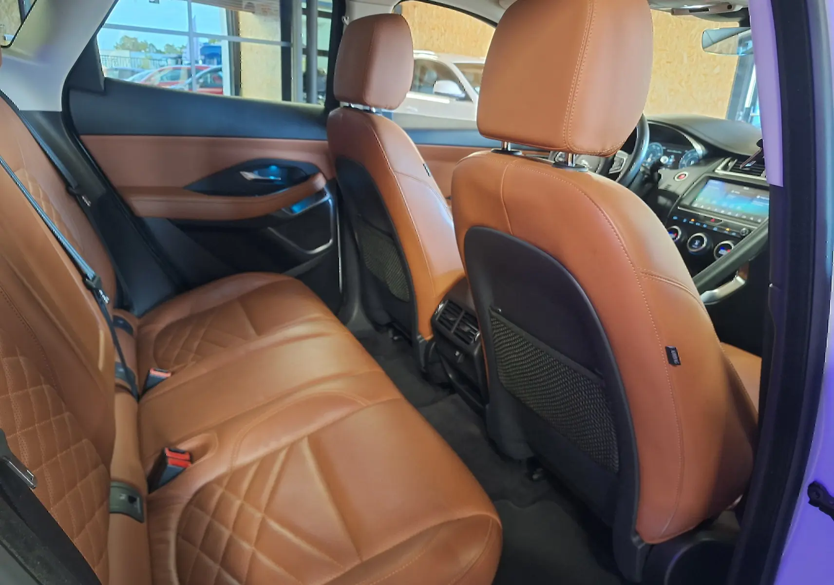 Vue intérieure arrière côté droit du Jaguar E-PACE 2019 avec sièges en cuir marron et tableau de bord visible.