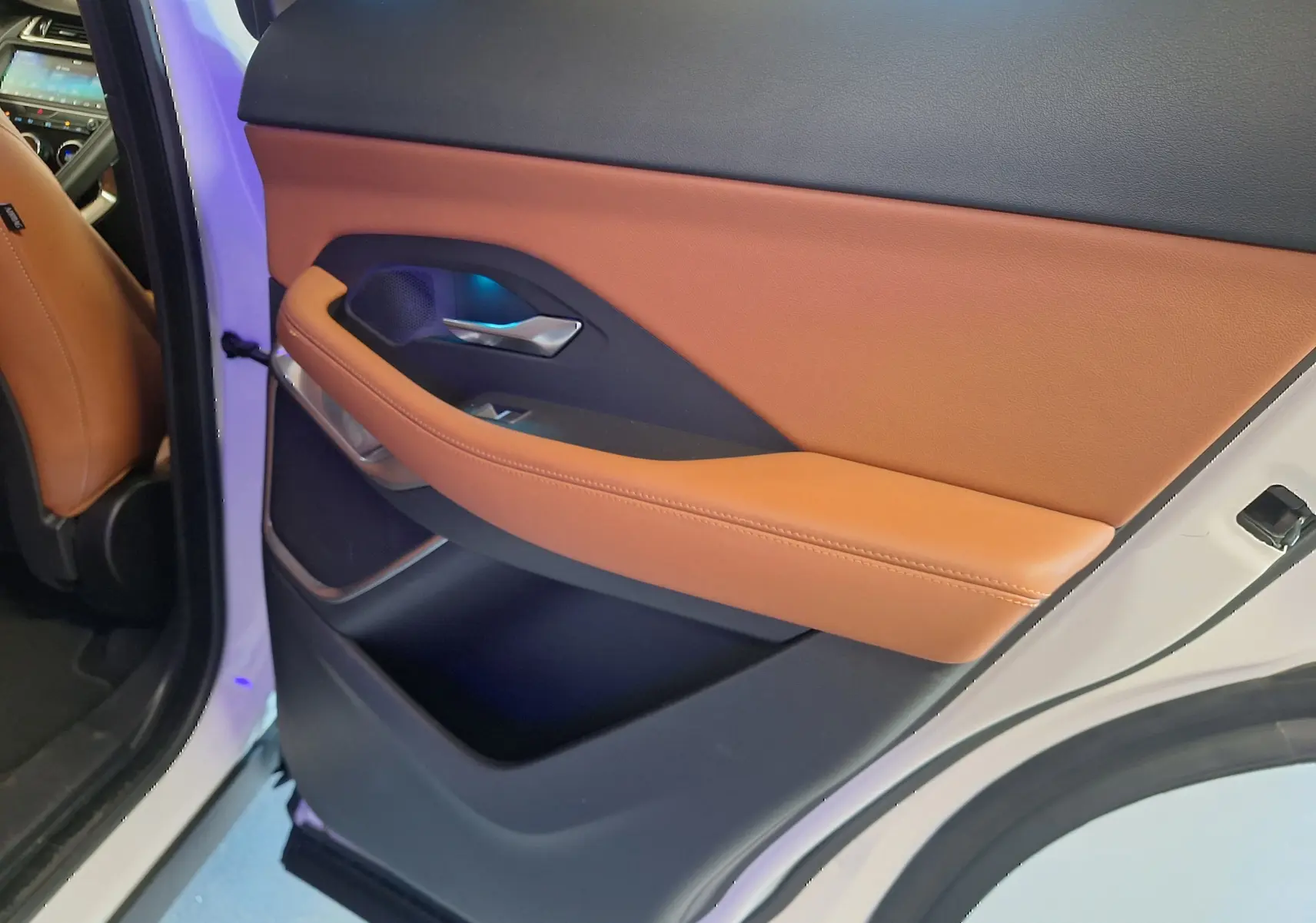 Vue intérieure de la porte arrière droite d’un Jaguar E-PACE blanc avec garniture cuir marron et détails noirs.