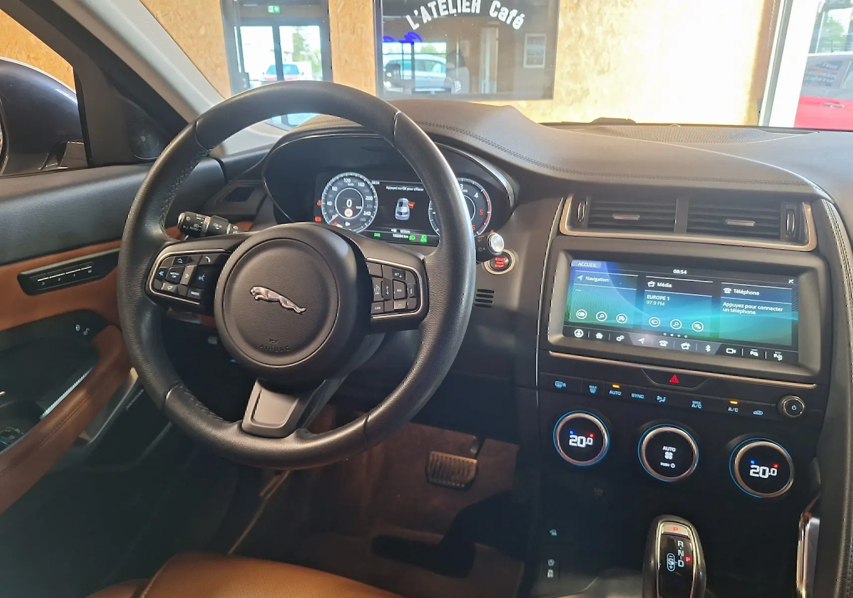 Vue intérieure avant du Jaguar E-PACE 2019, volant cuir noir et tableau de bord avec écran tactile couleur.