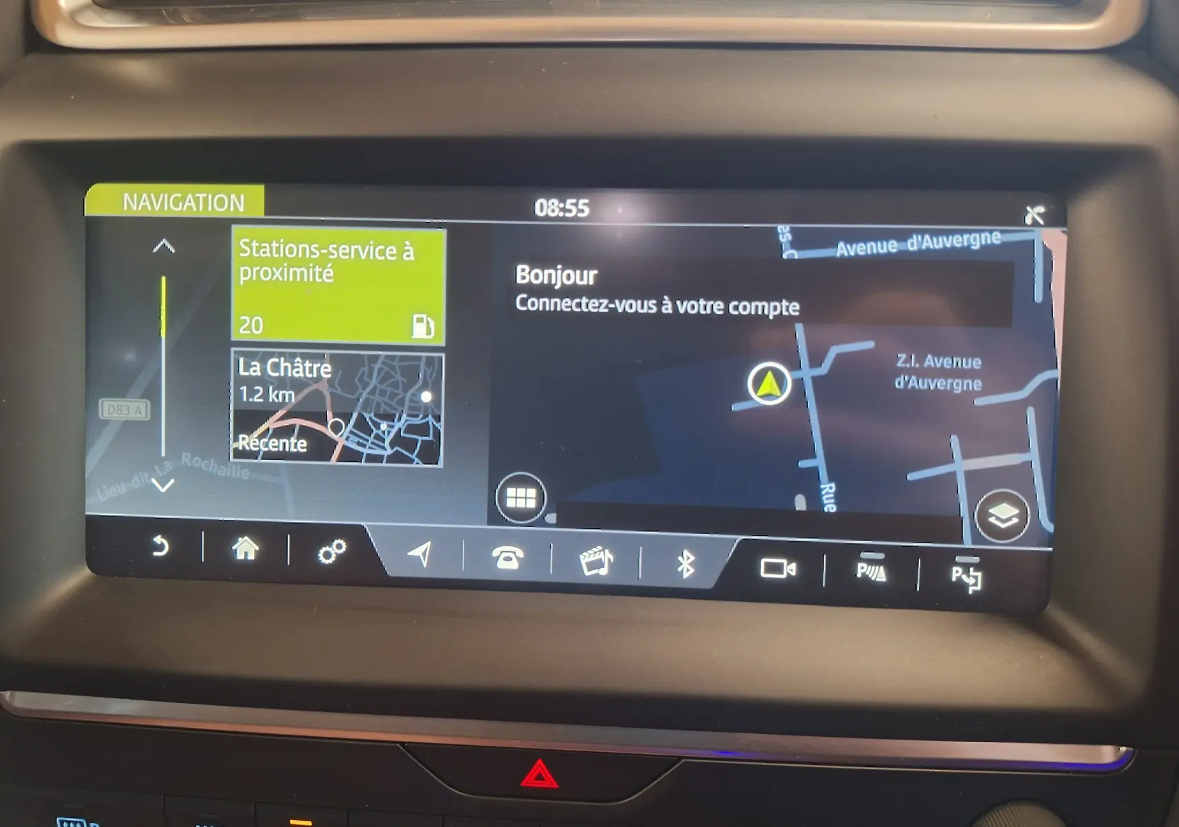 Écran tactile de navigation du Jaguar E-PACE blanc, affichant une carte avec stations-service à proximité.