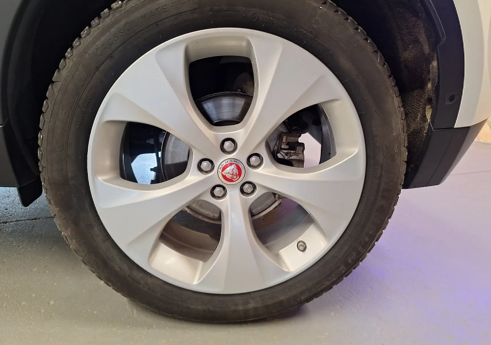 Gros plan sur la roue avant droite blanche du Jaguar E-PACE 2.0 D180 R-DYNAMIC HSE avec jante alliage cinq branches.