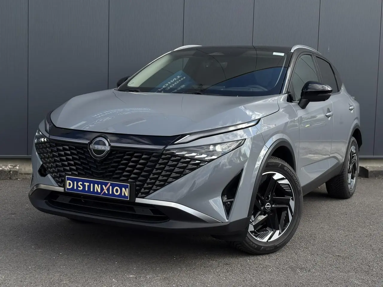 Nissan Qashqai gris Ceramic en 3/4 avant droit, avec calandre noire texturée et jantes alliage bicolores.