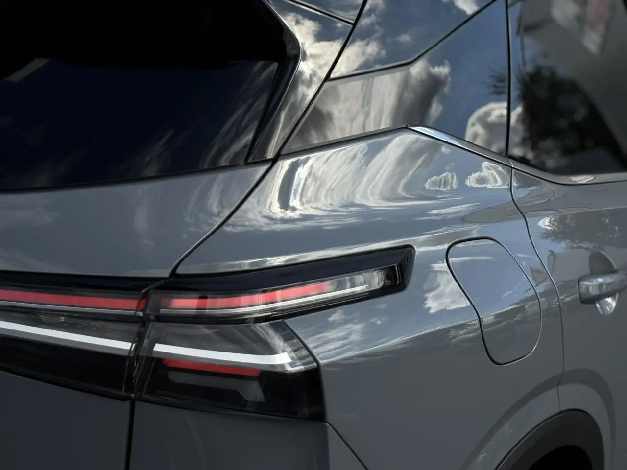 Gros plan sur l'arrière droit du Nissan Qashqai gris Ceramic, mettant en valeur le feu arrière LED et la trappe à carburant.