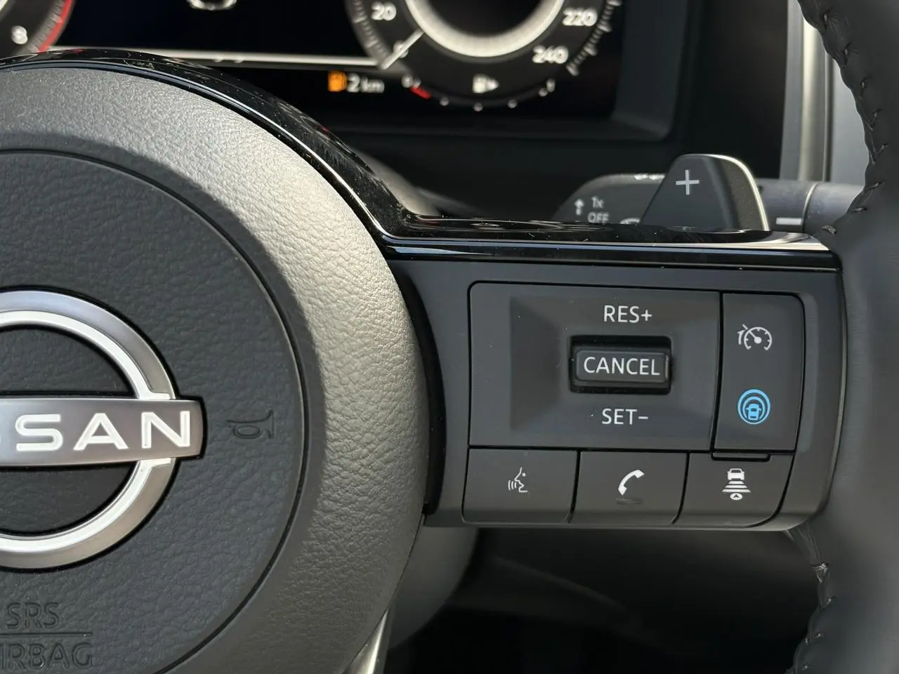Gros plan sur les commandes à droite du volant cuir du Nissan Qashqai 2025, avec régulateur de vitesse et assistance active.