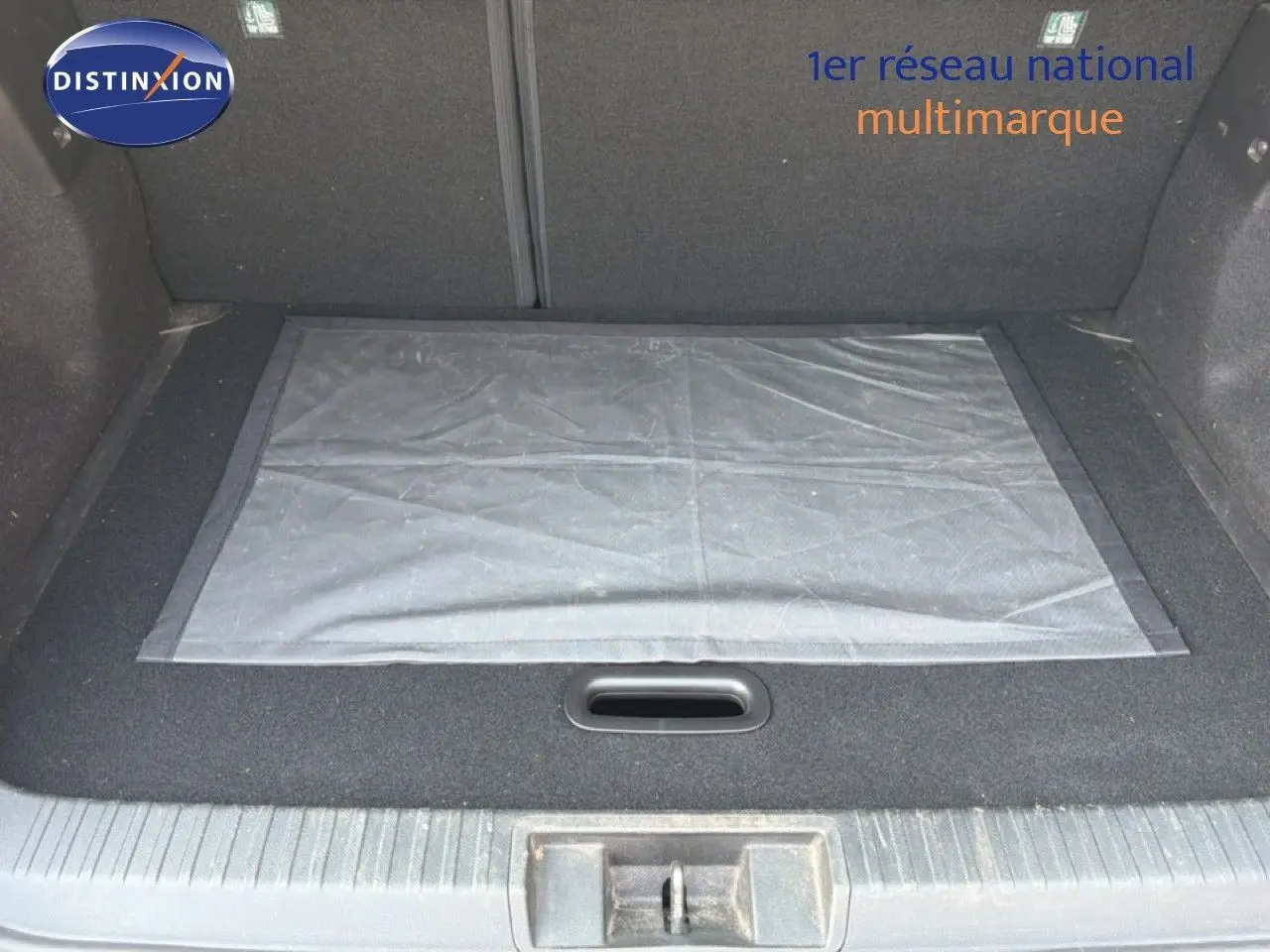 Coffre ouvert d’un Renault Captur 2022 bleu marine fumé, vue intérieure montrant le tapis de sol et le revêtement noir.