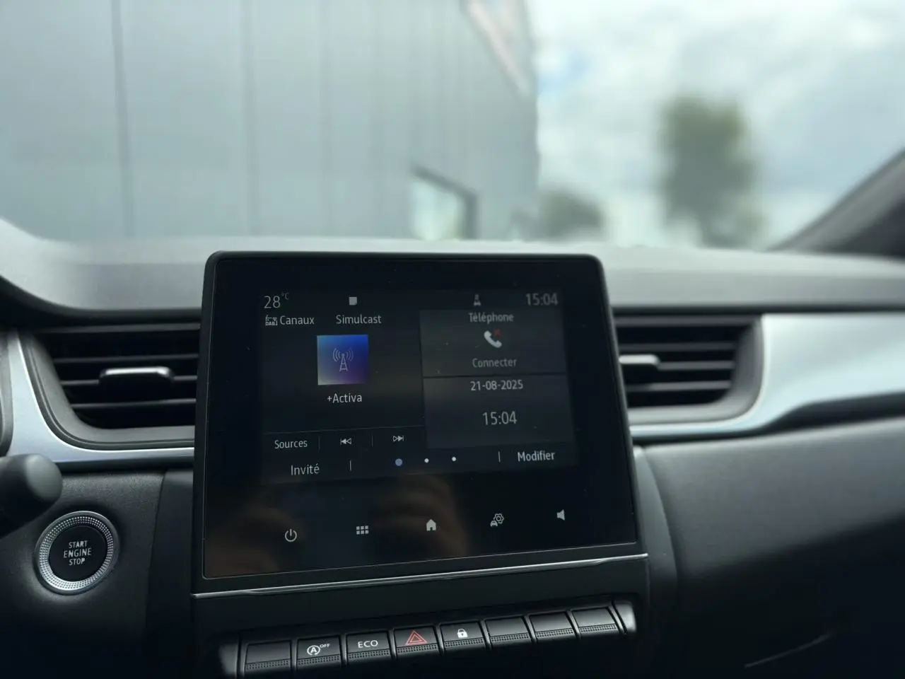 Vue intérieure centrée sur l'écran tactile Easy Link 7" du Renault Captur blanc nacré 2022 avec bouton start/stop.