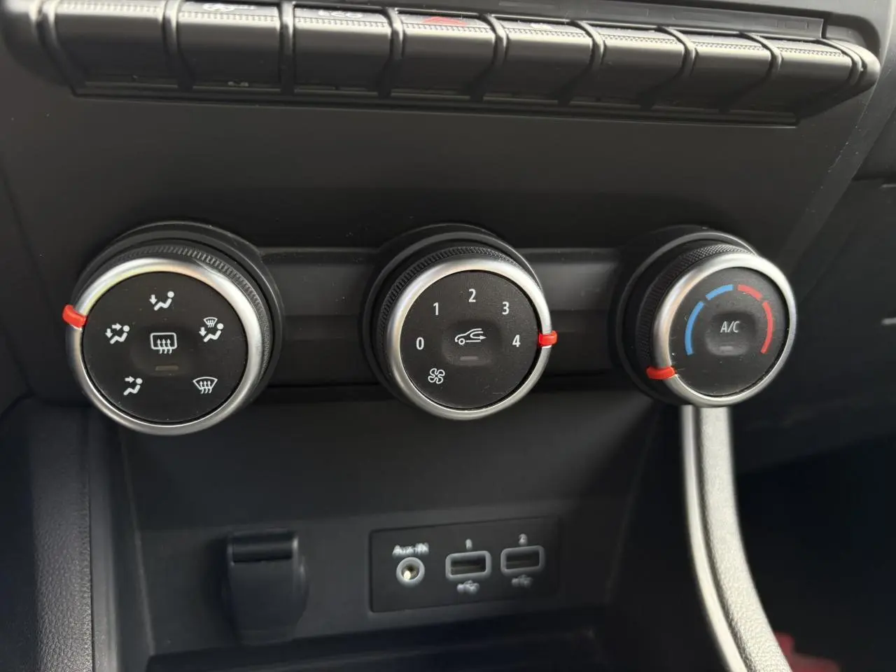 Commandes manuelles de climatisation avec trois molettes noires et prises USB sur la console centrale du Renault Captur blanc nacré 2022.