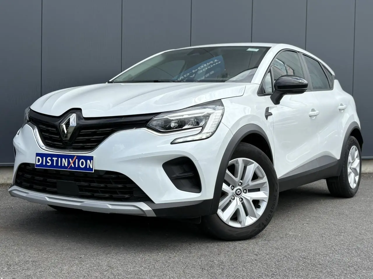 Renault Captur blanc nacré vu de 3/4 avant droit avec calandre noire et jantes argentées.