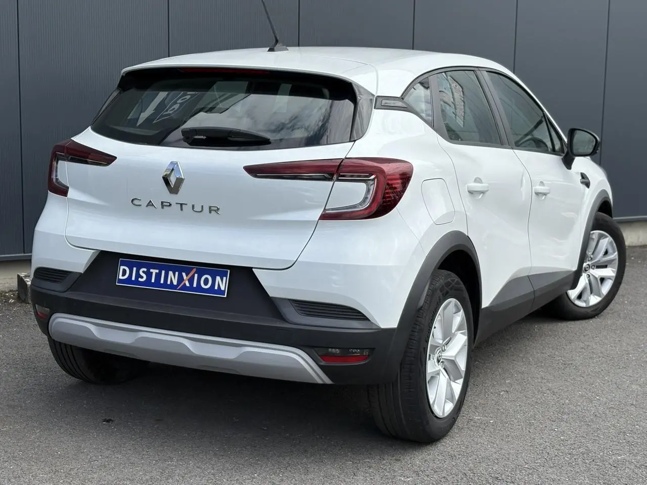 Vue 3/4 arrière droite d'un Renault Captur blanc nacré 2022 avec feux arrière LED et plaque Distinxion.