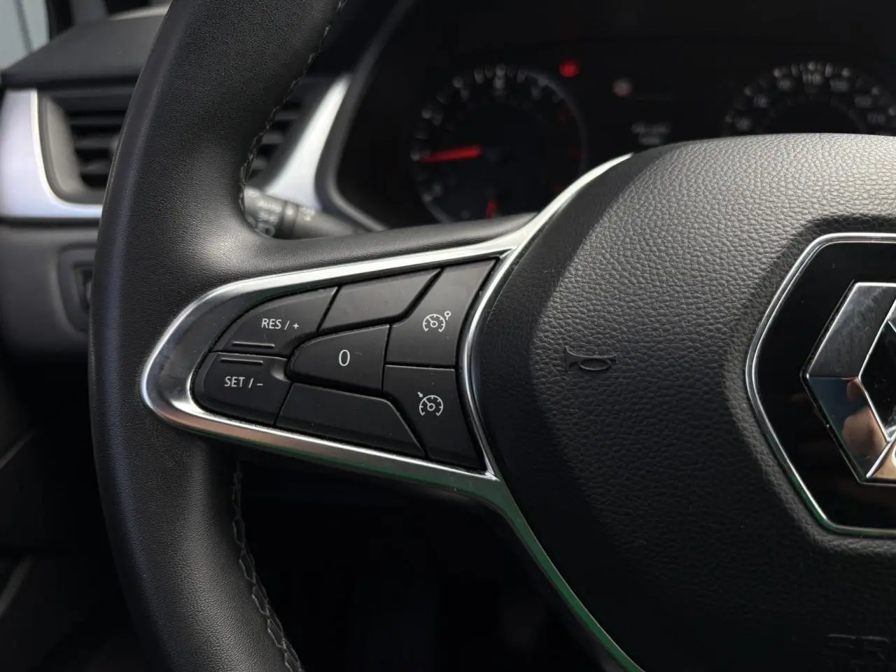 Gros plan sur le volant noir du Renault Captur TCE 90 Business 2022, avec commandes de régulateur de vitesse.