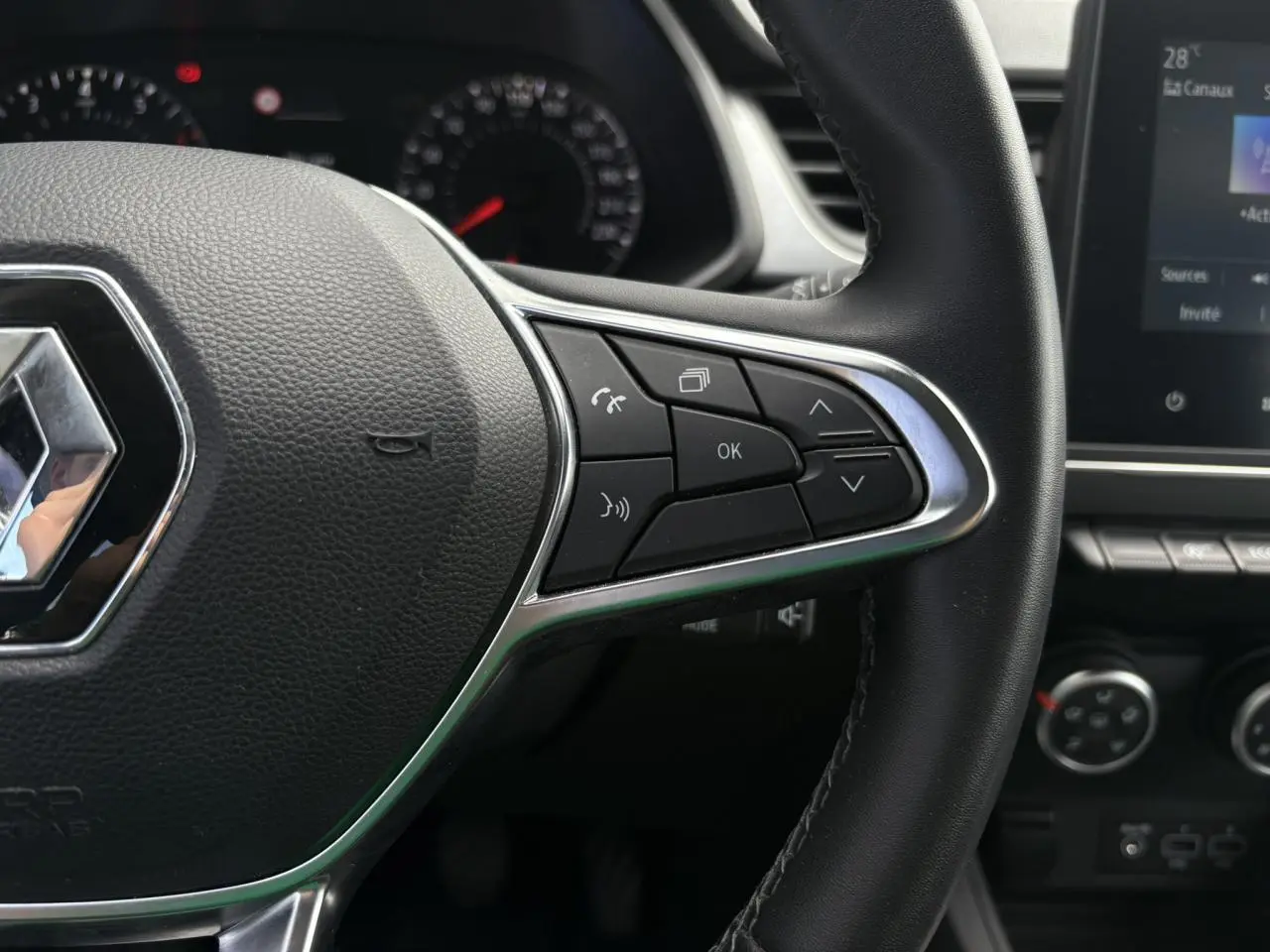 Gros plan sur le volant noir du Renault Captur 2022 avec commandes multifonctions et tableau de bord partiellement visible.