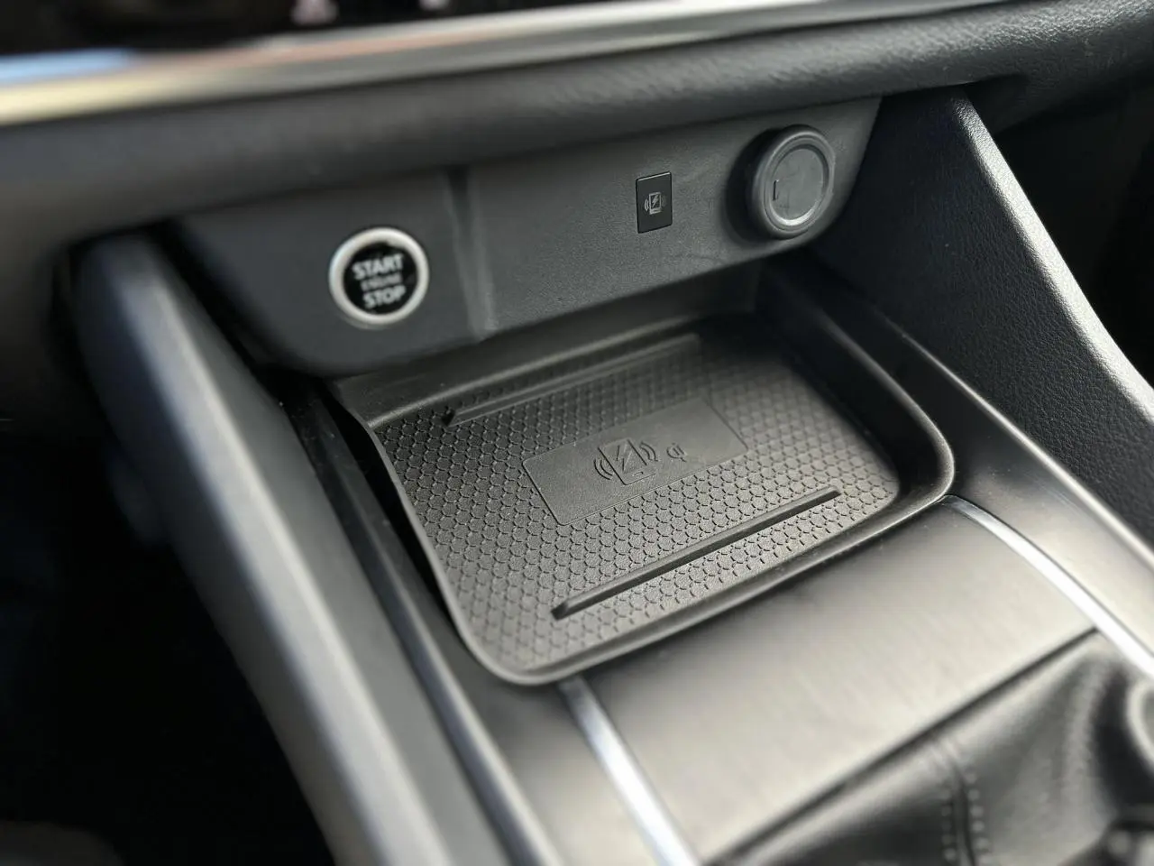 Gros plan sur la console centrale noire du Nissan Qashqai 2024, avec zone de recharge sans fil et bouton Start/Stop.