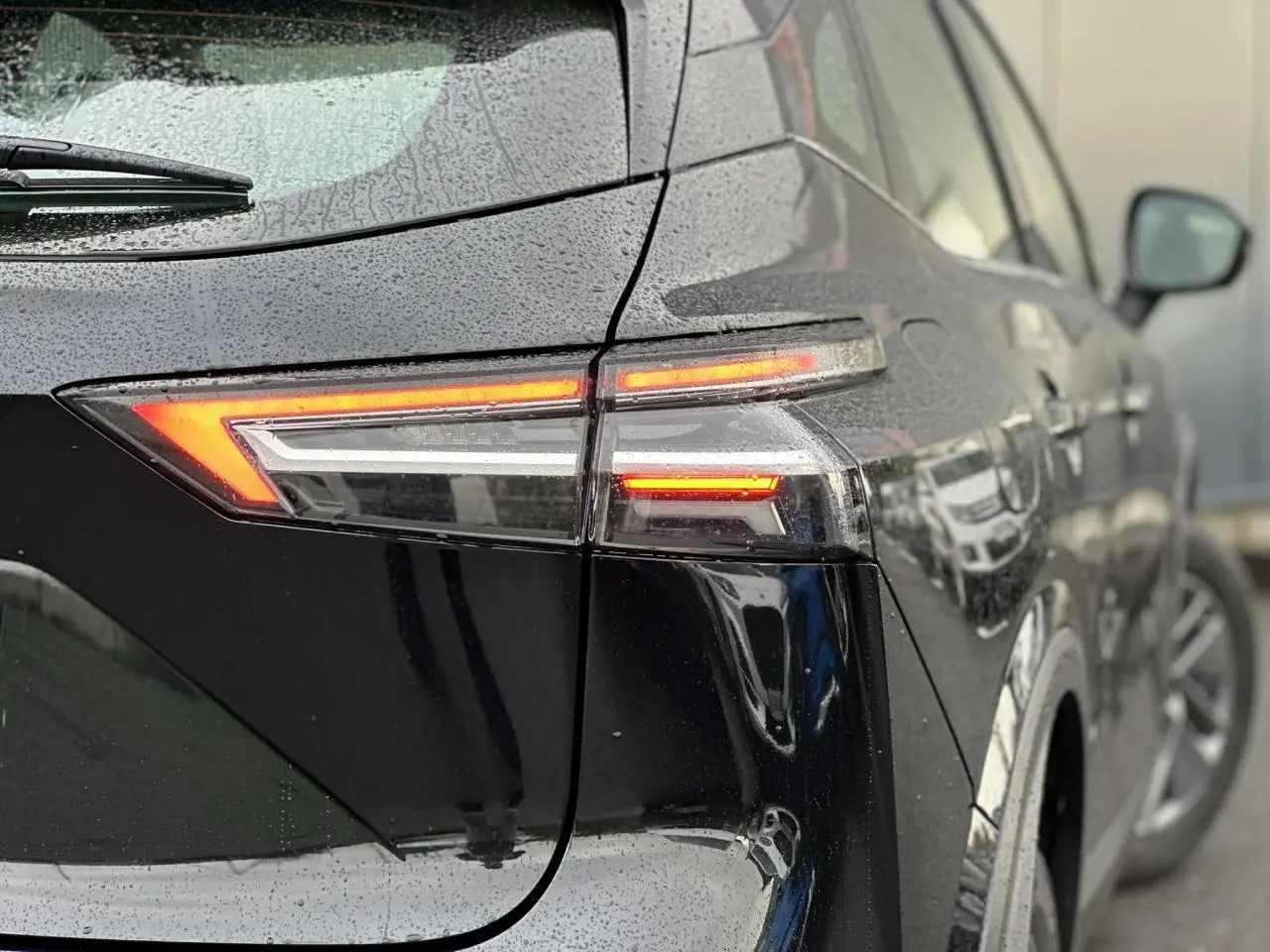 Feu arrière droit allumé d'un Nissan Qashqai noir nacré 2024, vue rapprochée sous la pluie.