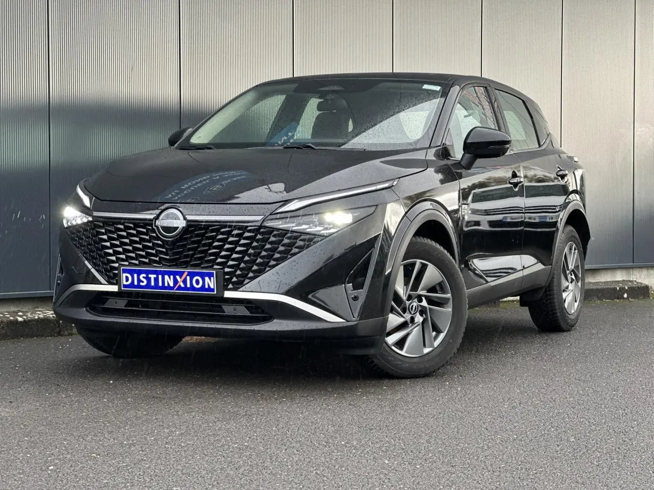 Nissan Qashqai noir nacré vu de 3/4 avant droit avec calandre distinctive et feux LED allumés.