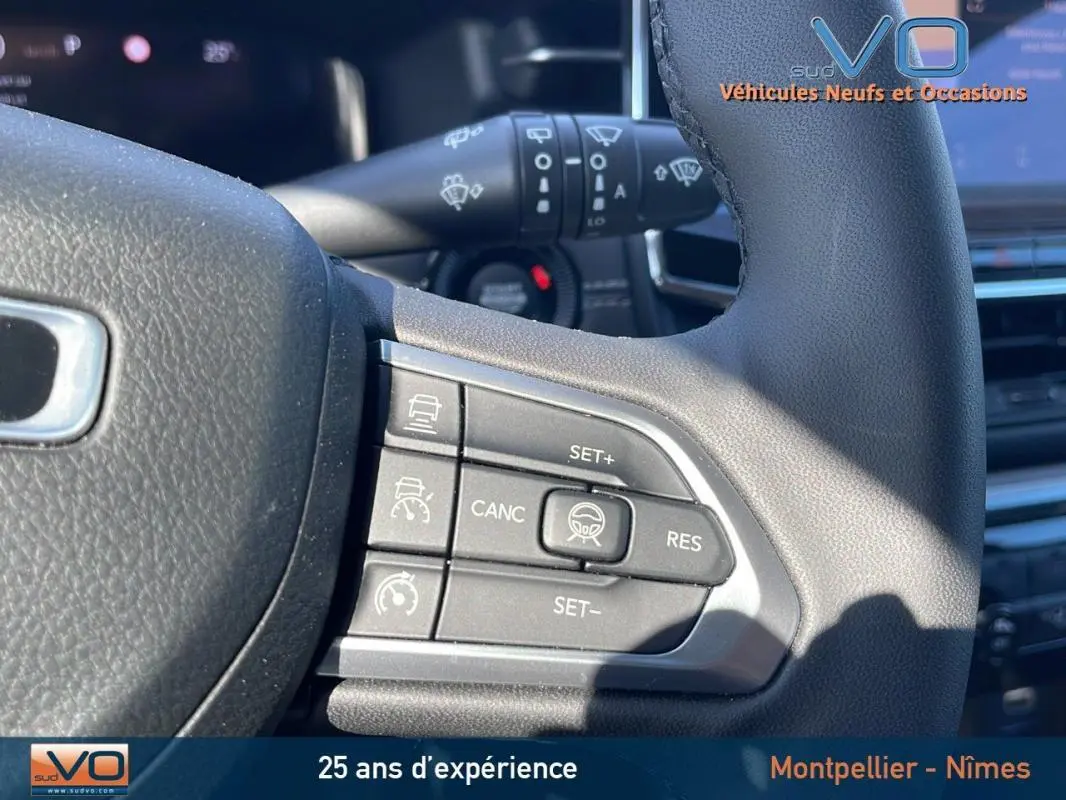 Gros plan sur les commandes du régulateur de vitesse au volant d'un Jeep Compass noir 2023, intérieur moderne.