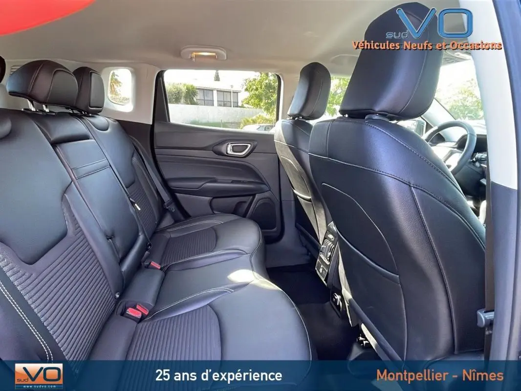 Vue intérieure arrière du Jeep Compass 2023 avec sièges cuir noirs et accoudoir central visible côté droit.