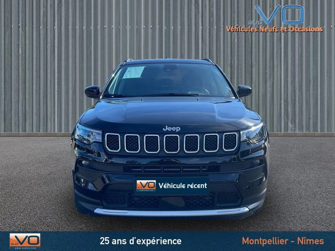 Vue frontale d'un Jeep Compass noir 2023 avec calandre distinctive et phares LED allumés sur fond neutre.