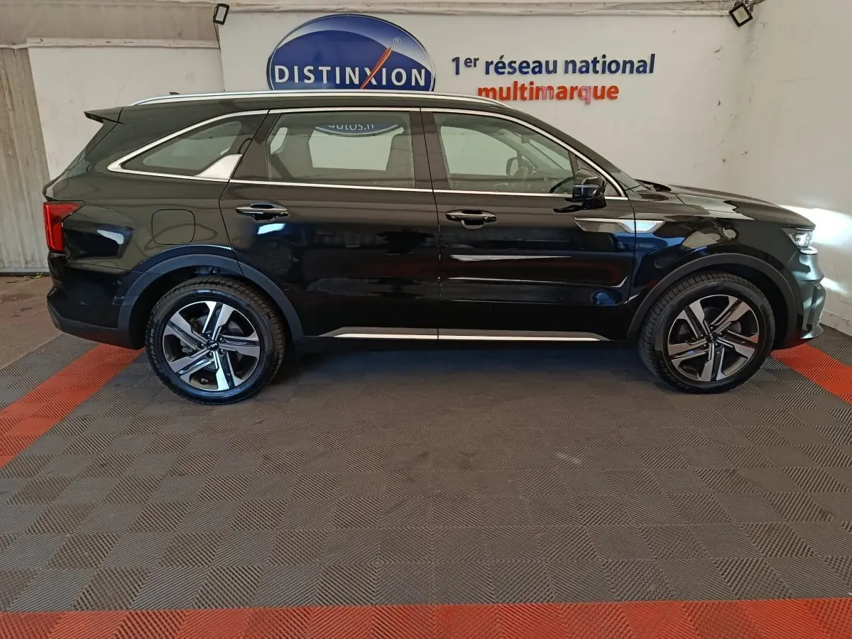 Vue latérale droite du KIA Sorento noir 2023 avec jantes alliage et rails de toit chromés en intérieur showroom.
