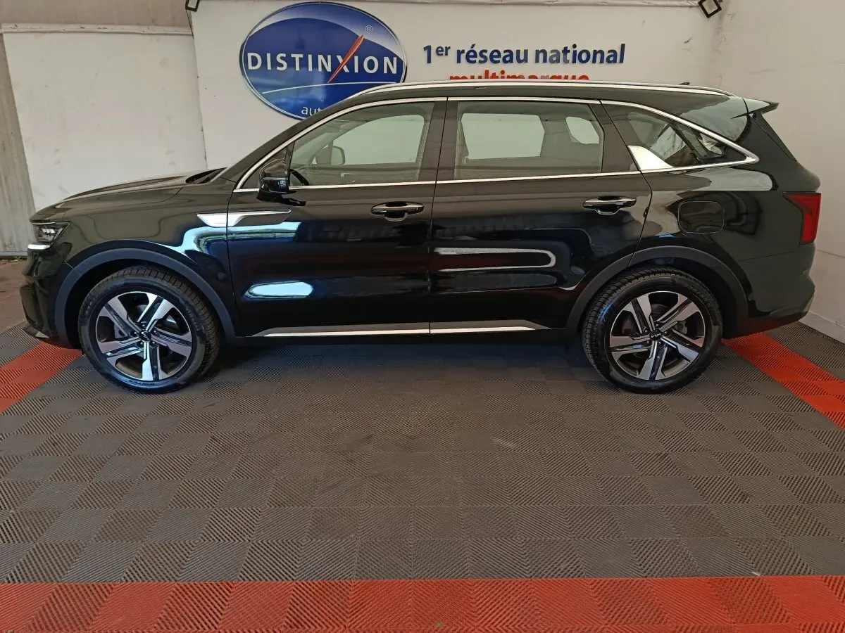 Vue de profil côté gauche du KIA Sorento noir 2023 hybride rechargeable, avec jantes alliage et toit chromé.