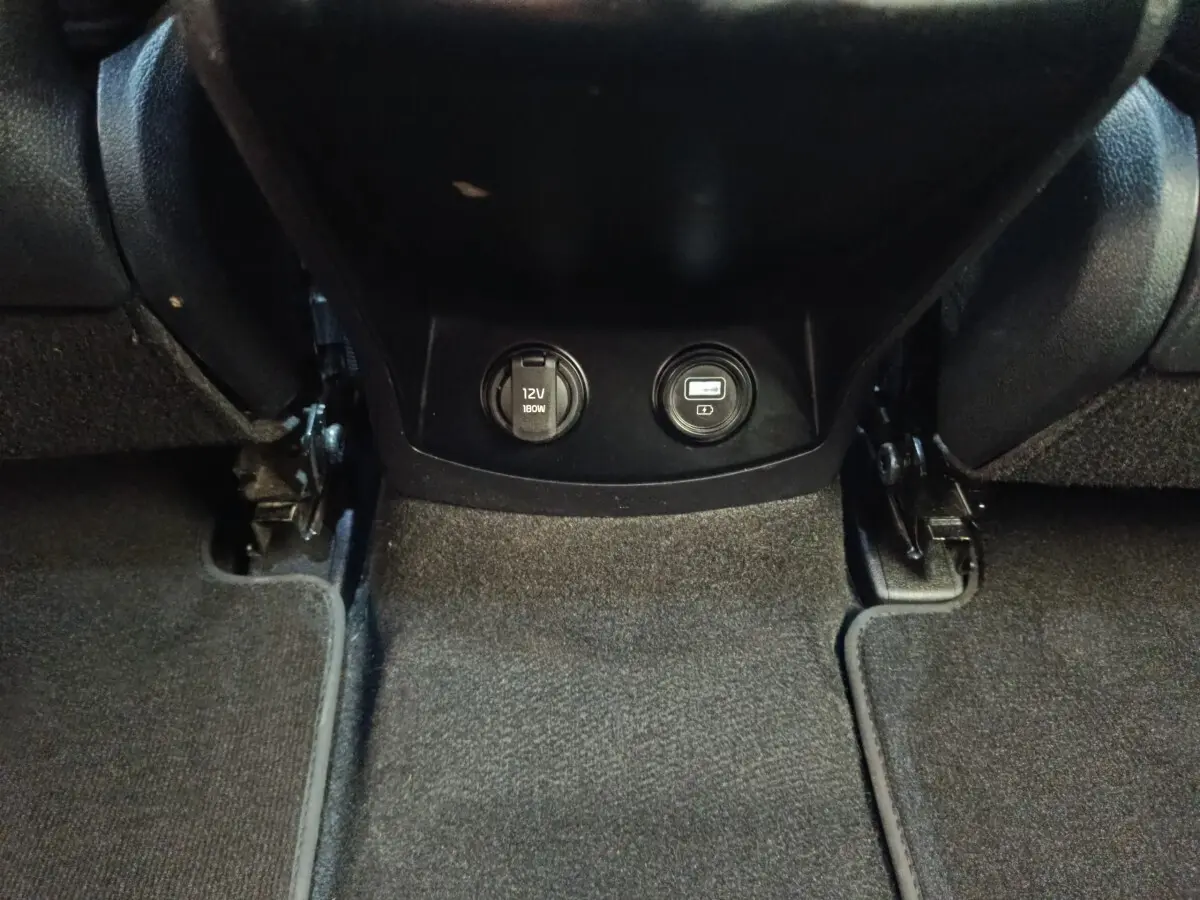 Prise 12V et port USB intégrés au bas de la console centrale, intérieur noir du Kia Sorento 2023 hybride rechargeable.