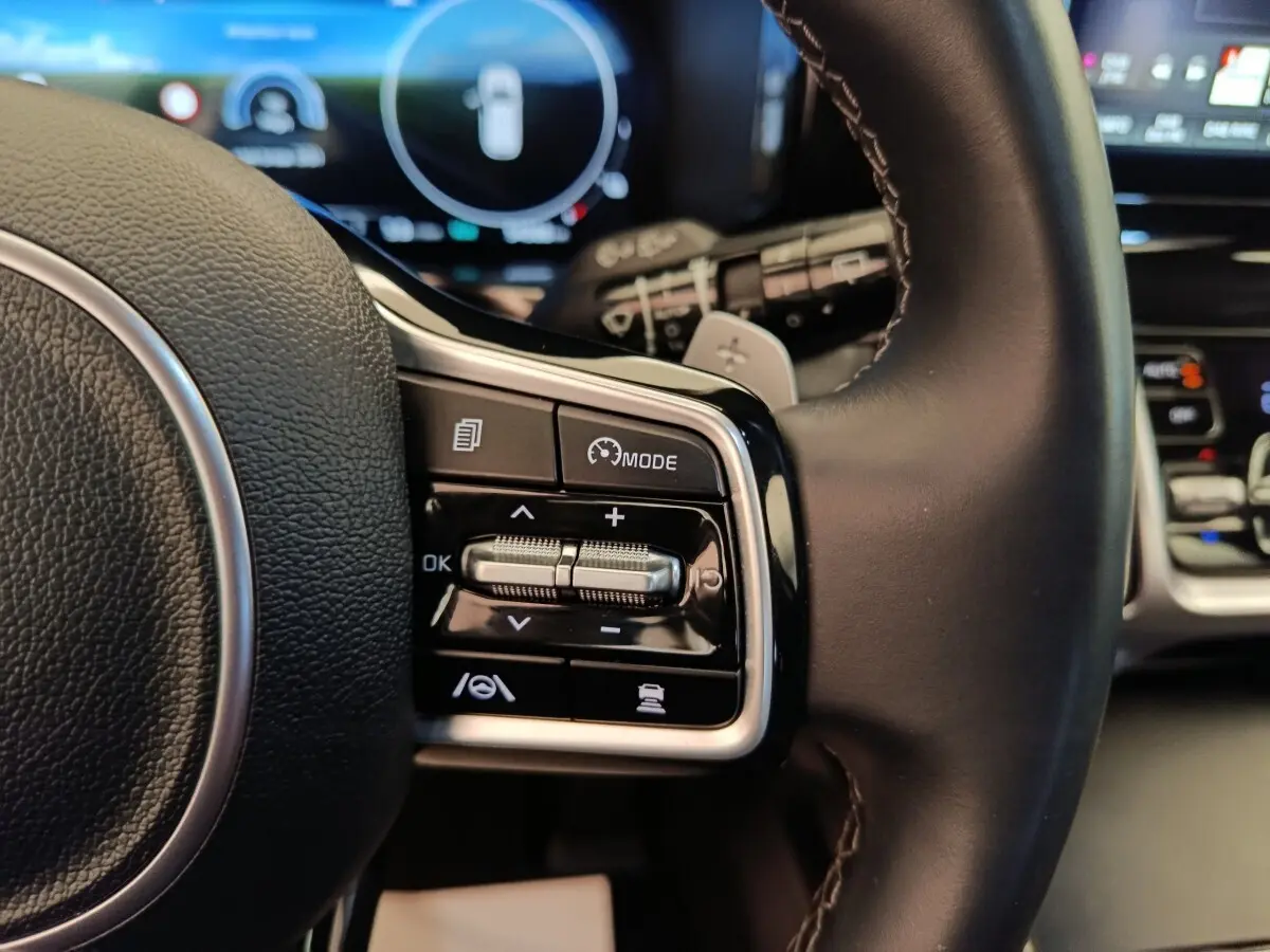 Gros plan sur les commandes multifonctions à droite du volant cuir noir du Kia Sorento hybride 2023.