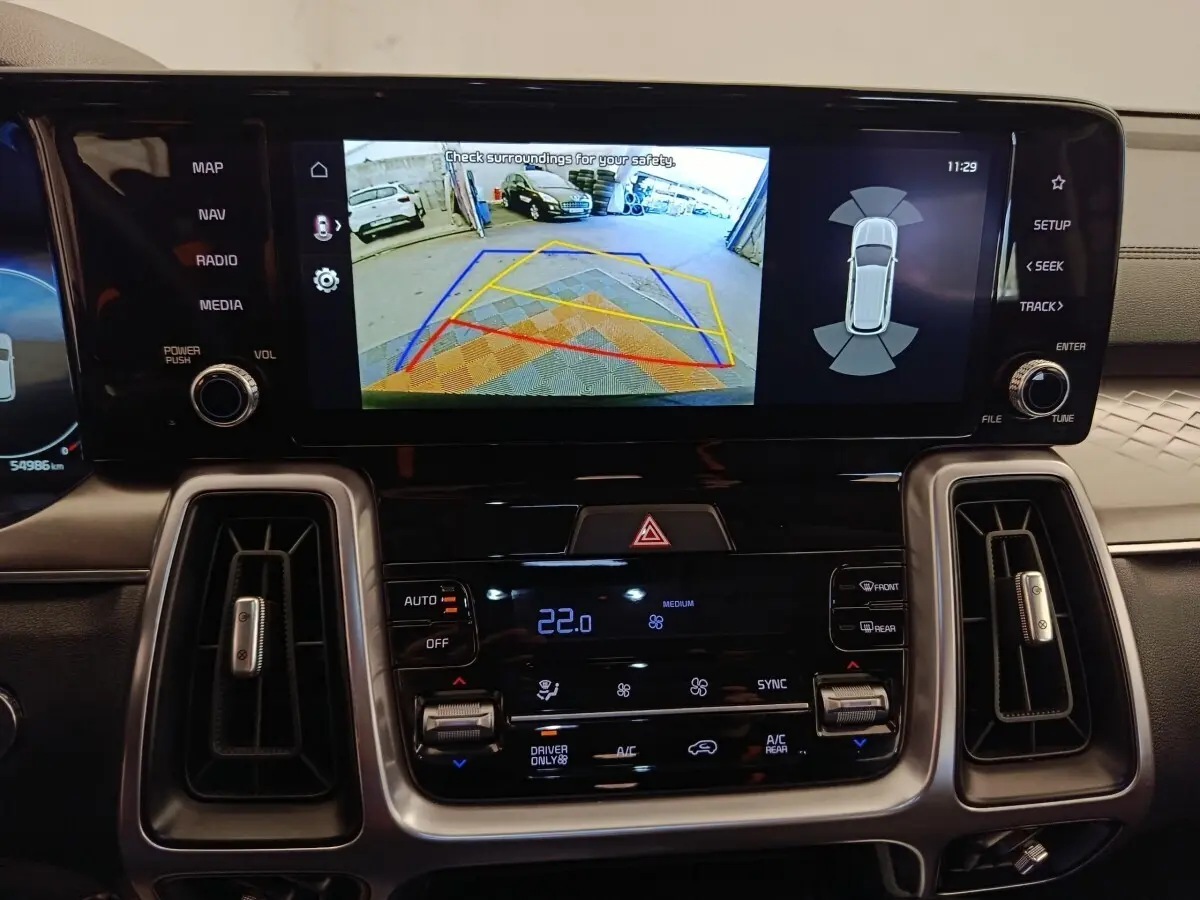 Vue rapprochée de l’écran tactile central du tableau de bord du Kia Sorento noir, affichant la caméra de recul et les commandes climatisation.