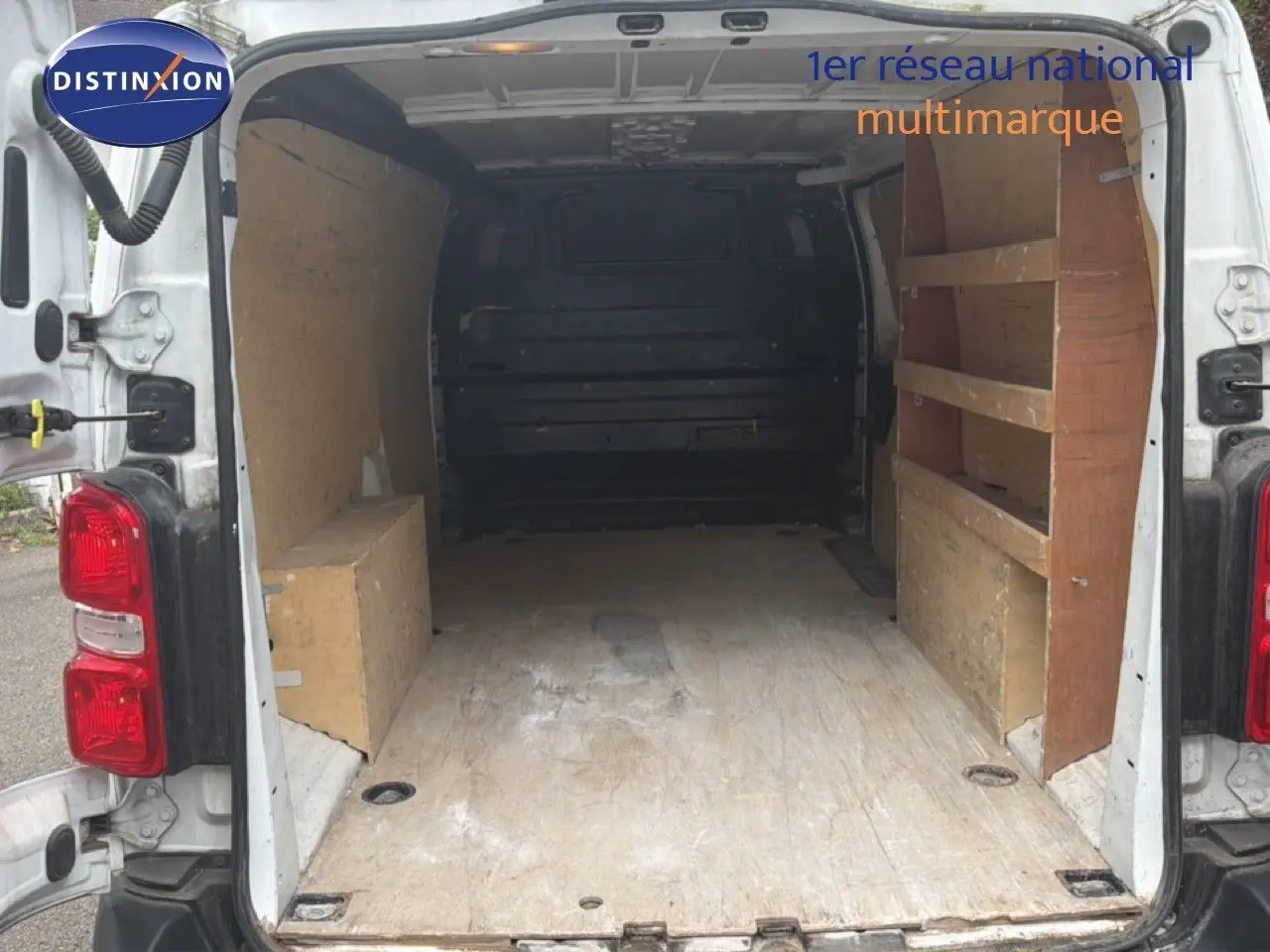 Vue arrière ouverte du Citroën Jumpy XL blanc de 2017, montrant l’espace de chargement avec étagères en bois.