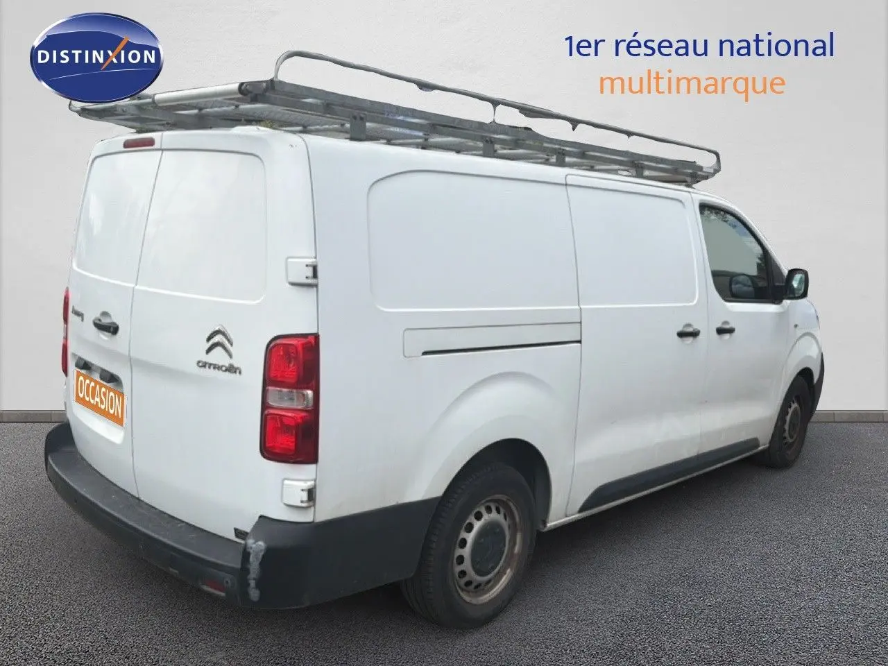 Vue 3/4 arrière droite d’un Citroën Jumpy blanc avec galerie de toit et pare-chocs arrière noir.