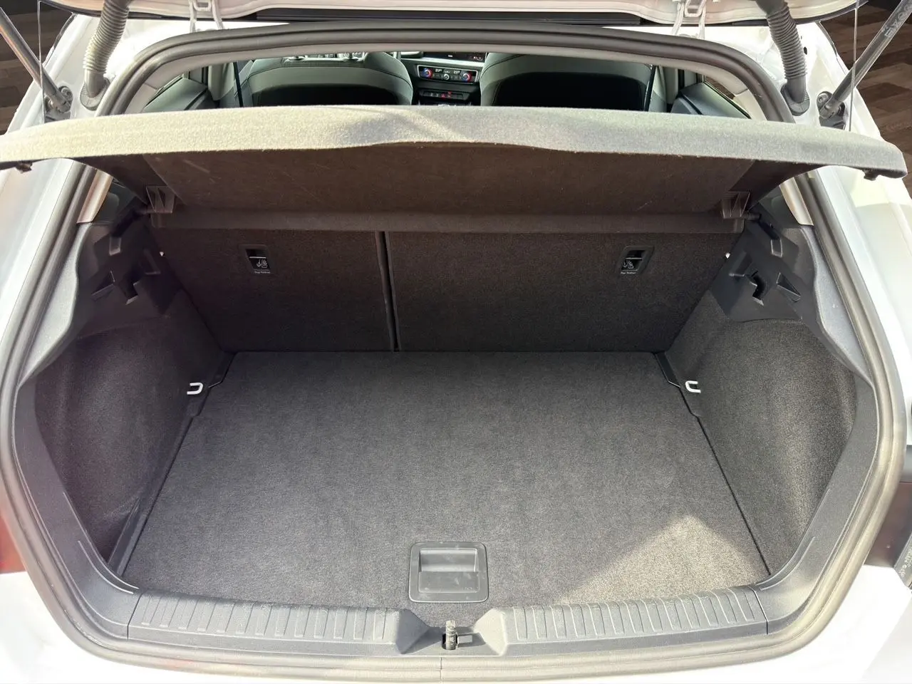 Coffre ouvert vu de l'arrière d'une Audi A1 Sportback blanche, montrant un espace de chargement propre et vide.