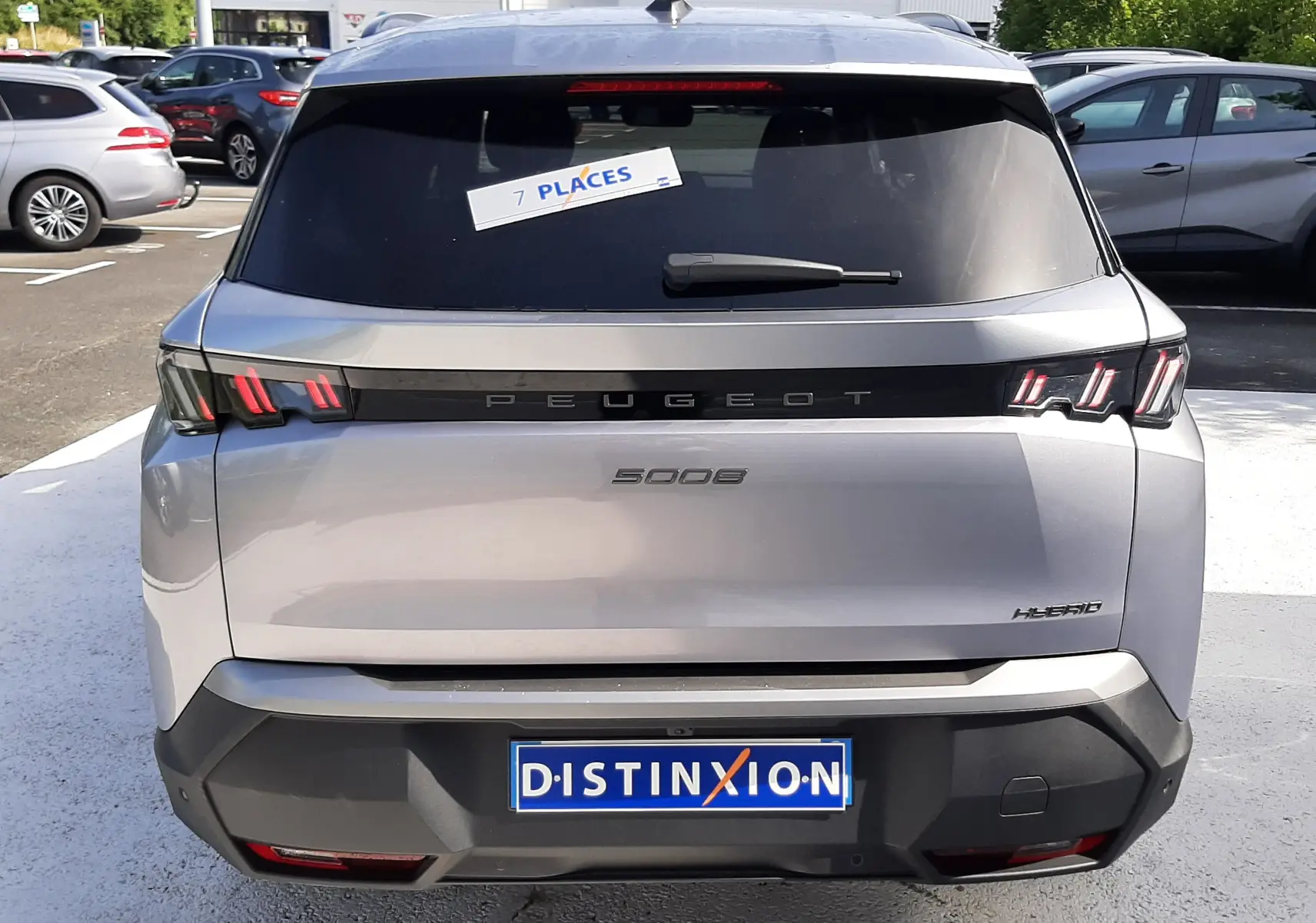 Vue arrière d'un Peugeot 5008 gris Artense Métal 2025 avec feux LED caractéristiques et sticker 7 places sur la vitre arrière.