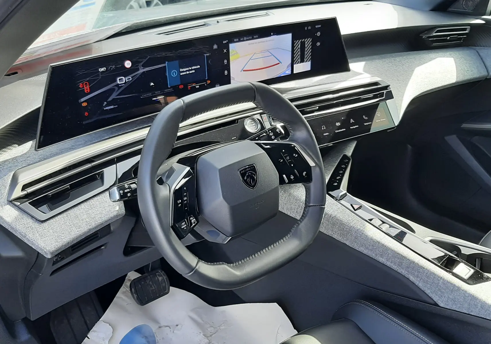 Vue intérieure du tableau de bord du Peugeot 5008 Hybrid 2025, avec volant compact et écran panoramique i-Cockpit.