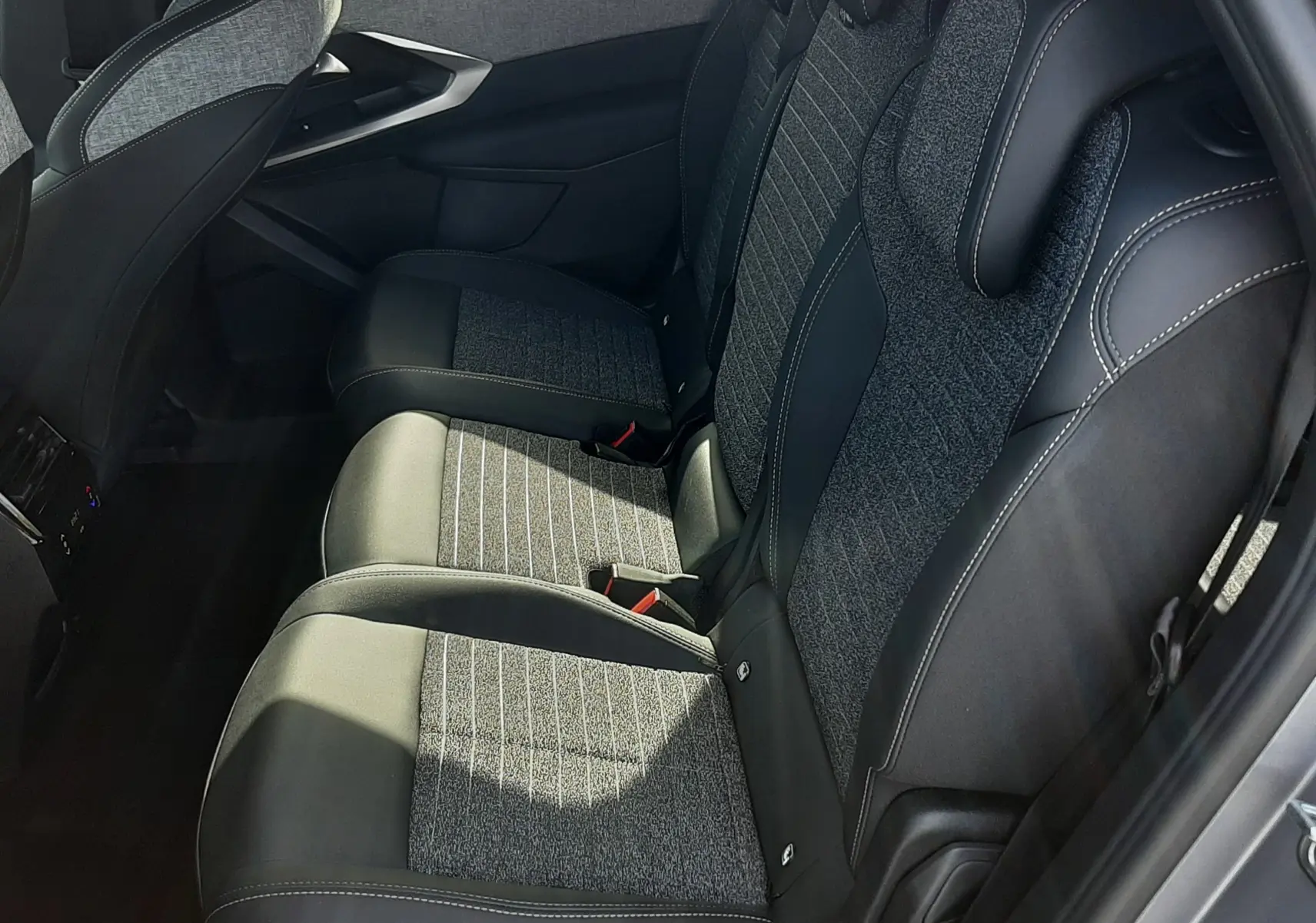 Vue latérale droite de la banquette arrière du Peugeot 5008 Hybrid 2025 avec sièges tissu et cuir gris noir.