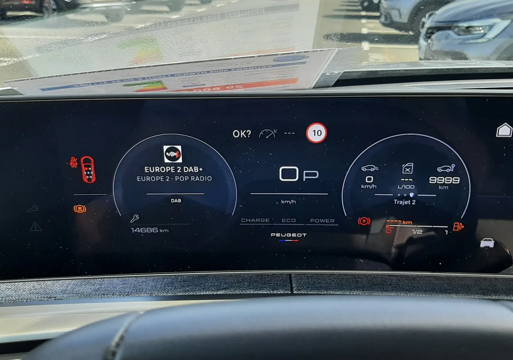 Vue intérieure du tableau de bord numérique du Peugeot 5008 Hybrid 2025, affichant la radio, la vitesse et l'autonomie.