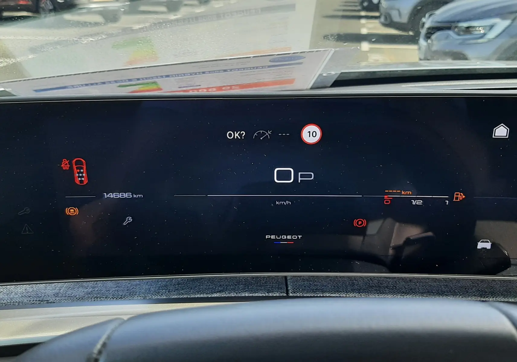 Vue rapprochée du tableau de bord numérique du Peugeot 5008 Hybrid gris, affichant la vitesse à 0 km/h et divers indicateurs.
