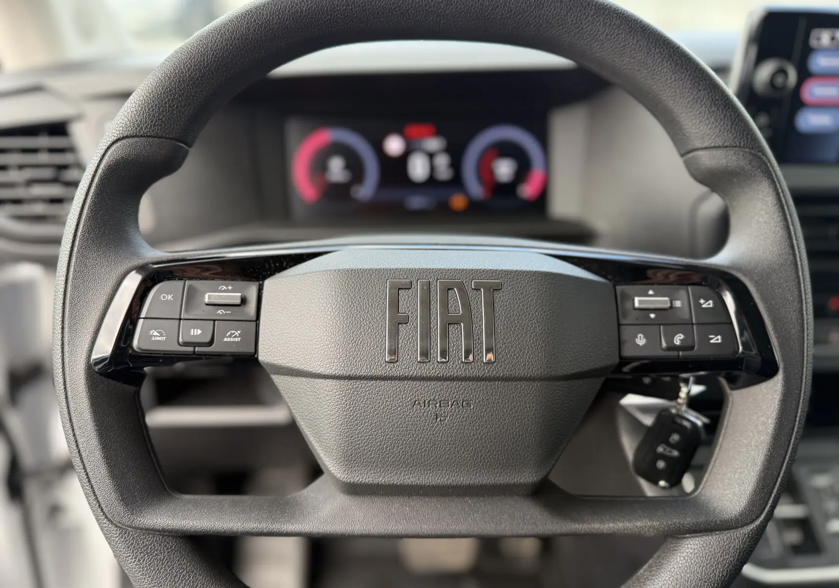 Gros plan sur le volant noir du FIAT Scudo Fourgon 2025 avec commandes intégrées et clé insérée à droite.