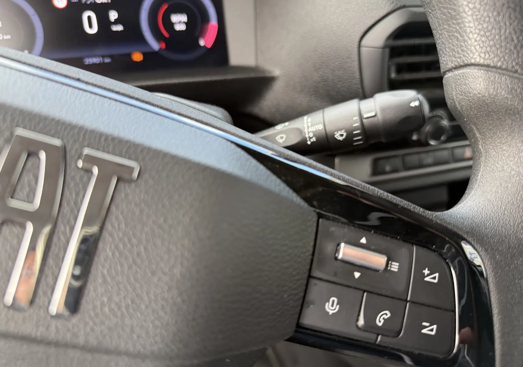 Gros plan sur le volant noir du Fiat Scudo Fourgon 2025 avec commandes audio et tableau de bord numérique en arrière-plan.