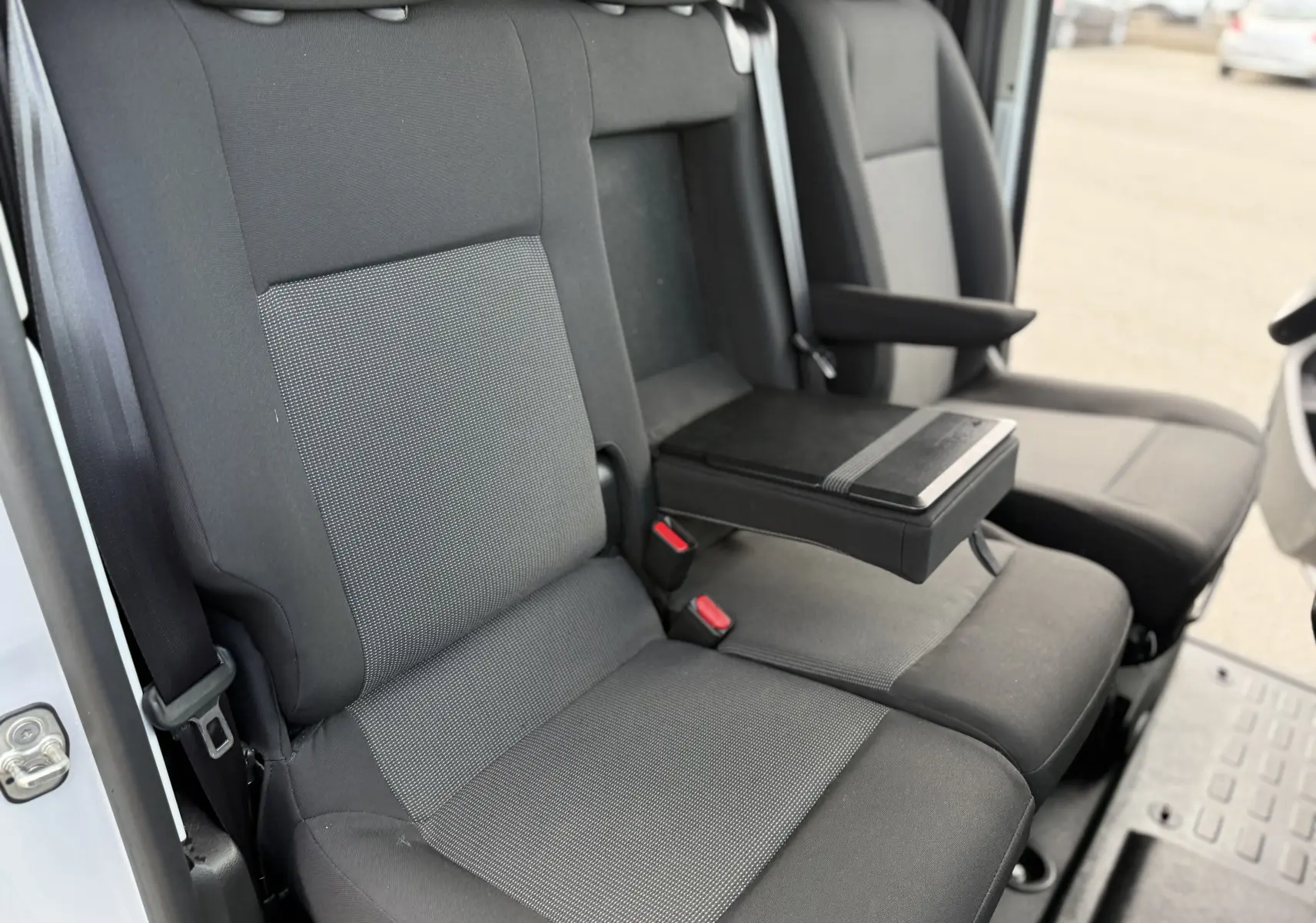 Vue intérieure rapprochée des sièges avant gris foncé du Fiat Scudo Fourgon, avec accoudoir central déployé.
