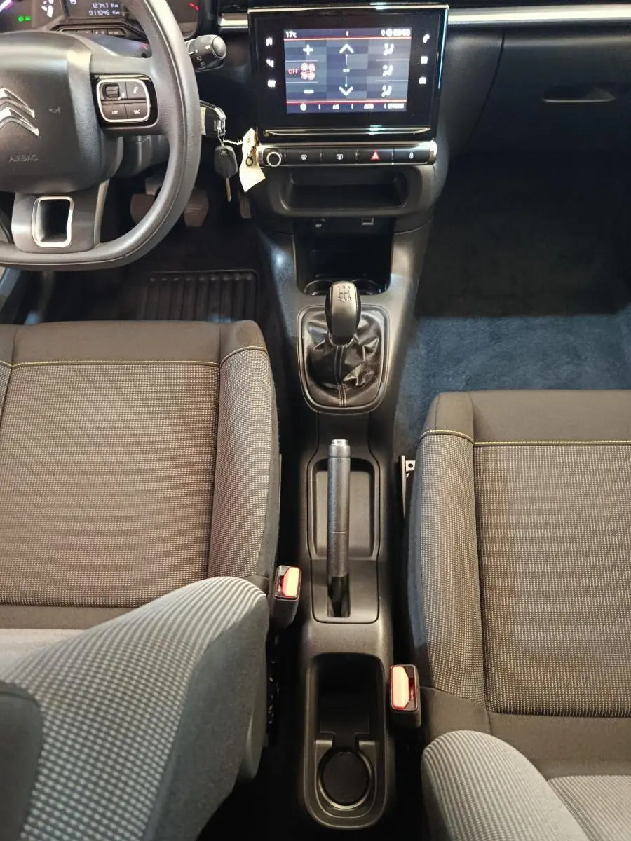 Vue intérieure centrée sur la console centrale et le levier de vitesse manuel de la Citroën C3 gris foncé 2024.