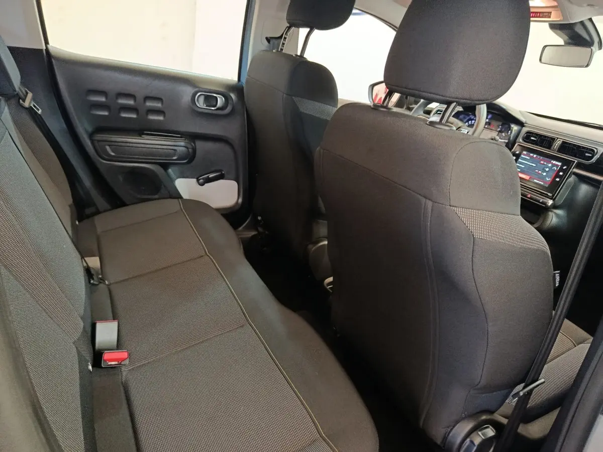 Vue intérieure arrière droite de la Citroën C3 2024 gris foncé, montrant la banquette et le tableau de bord tactile avant.