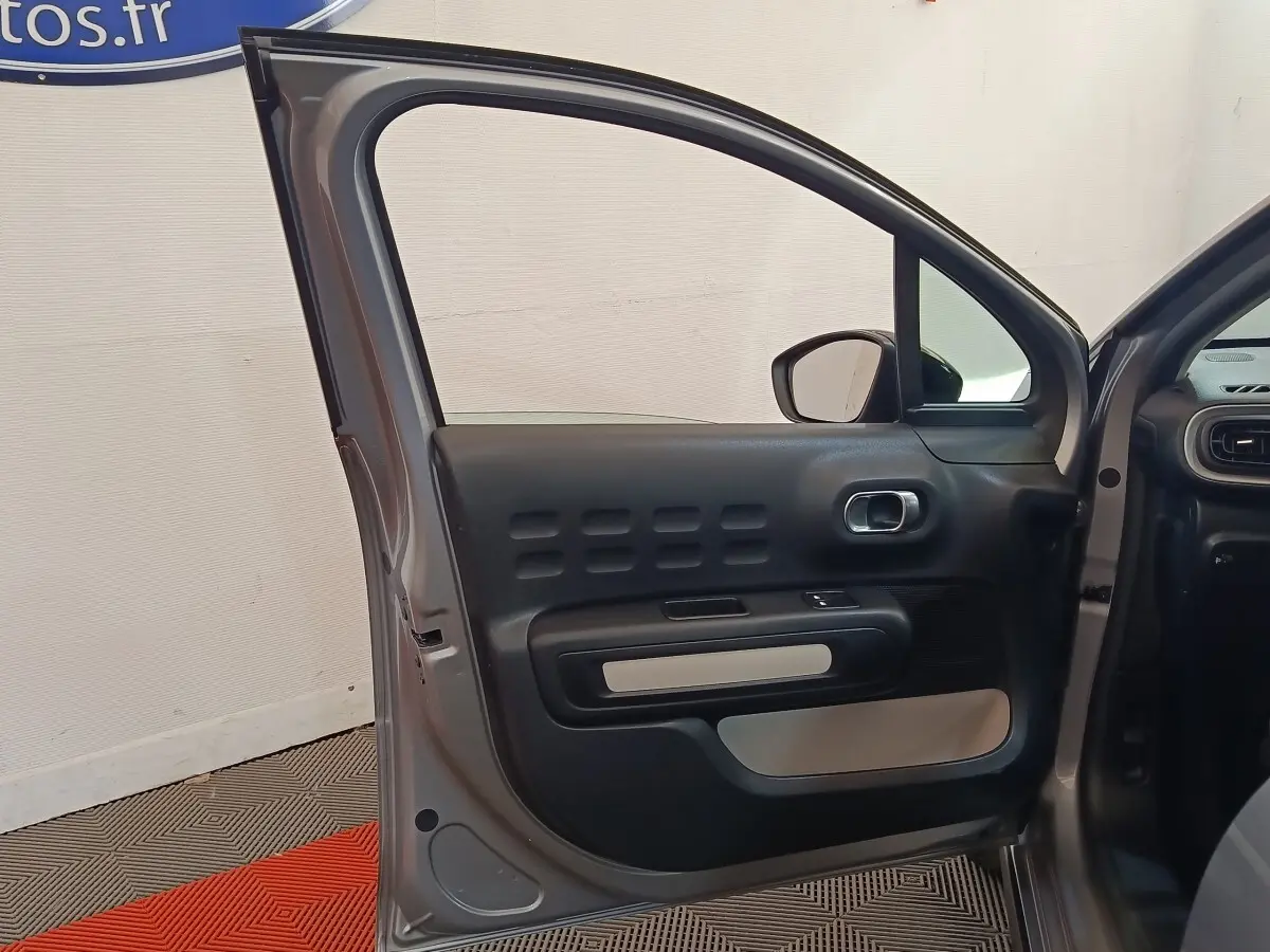 Vue intérieure de la porte avant gauche grise foncée d'une Citroën C3 2024 avec détails du panneau de porte noir et beige.
