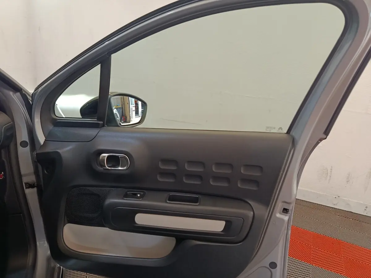 Vue intérieure du côté gauche de la porte arrière gris foncé de la Citroën C3 avec poignée chromée et inserts noirs.