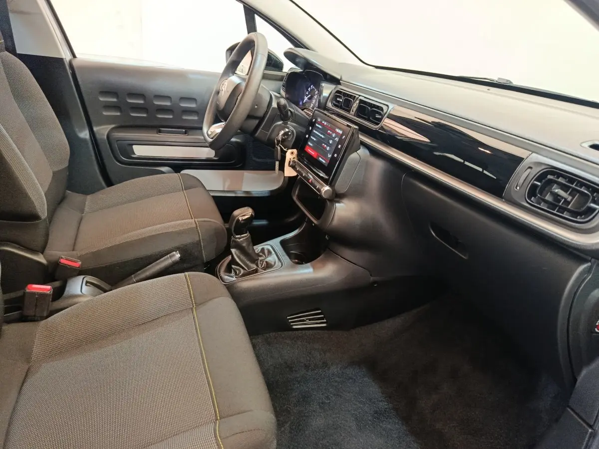 Intérieur de la Citroën C3 PureTech 83 2024, vue côté conducteur, tableau de bord noir avec écran tactile central.