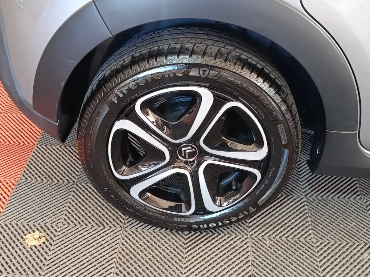 Gros plan sur la roue avant droite d'une Citroën C3 gris foncé avec jante noire et inserts argentés.
