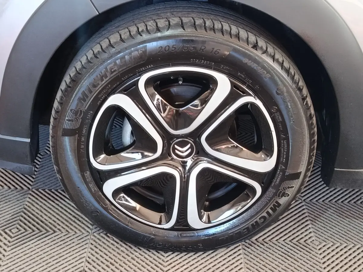 Gros plan sur la roue avant droite d'une Citroën C3 gris foncé avec jante alliage noire et argentée au design moderne.