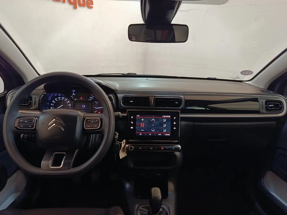 Vue intérieure frontale du tableau de bord de la Citroën C3 gris foncé 2024 avec écran tactile central et volant multifonctions.